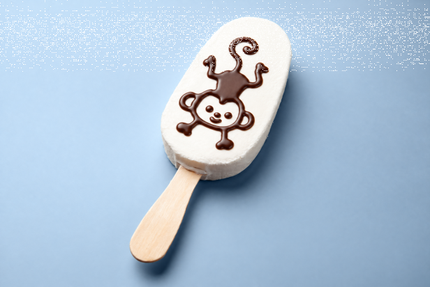 White ice cream bar on a stick decorated with a chocolate monkey